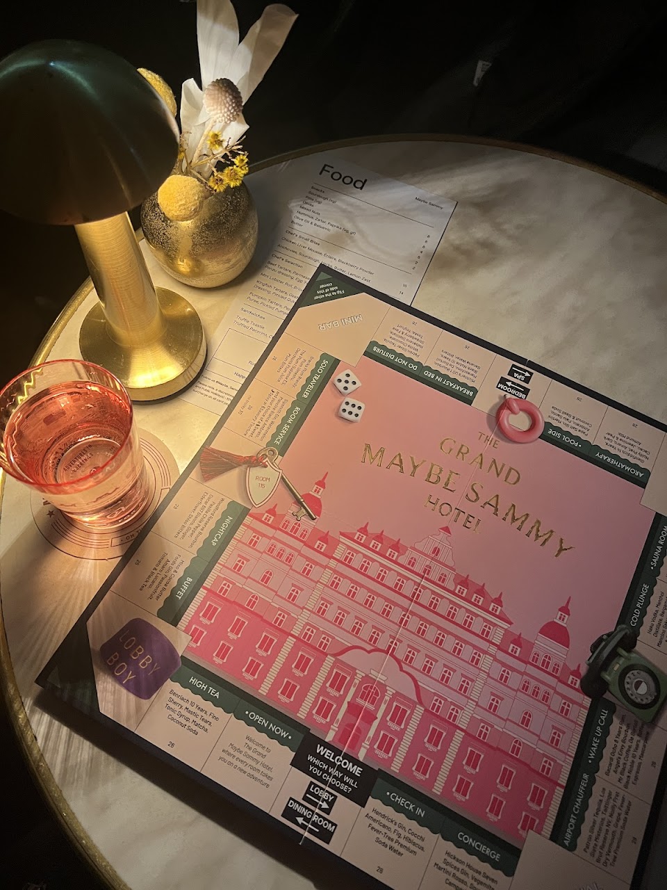 A Maybe Sammy illustrated cocktail menu on a marble table